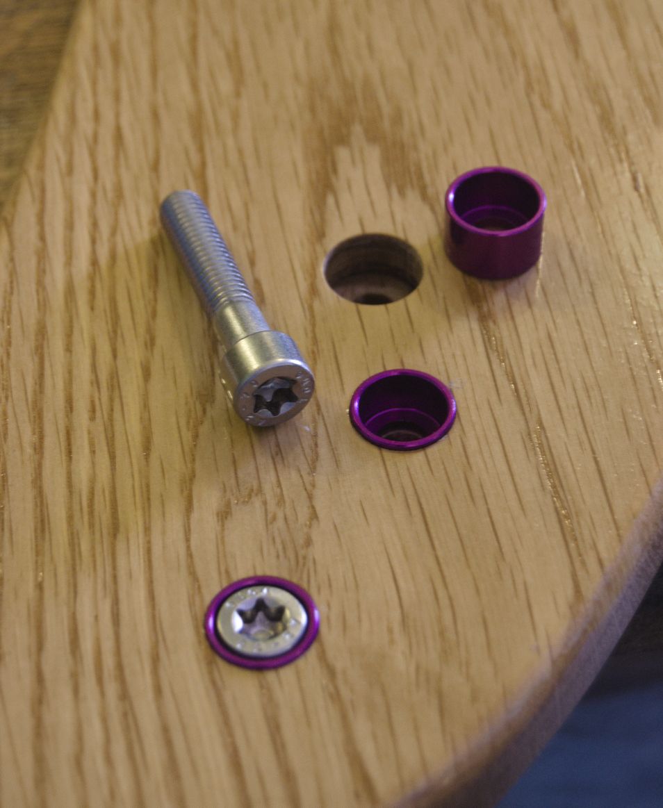 Three holes drilled into the wood. One is empty, showing how it only goes halfway into the wood before reducing in diameter. One has a cup washer inserted, and the last one was both a cup washer and a bolt inserted, showing how they sit flush.